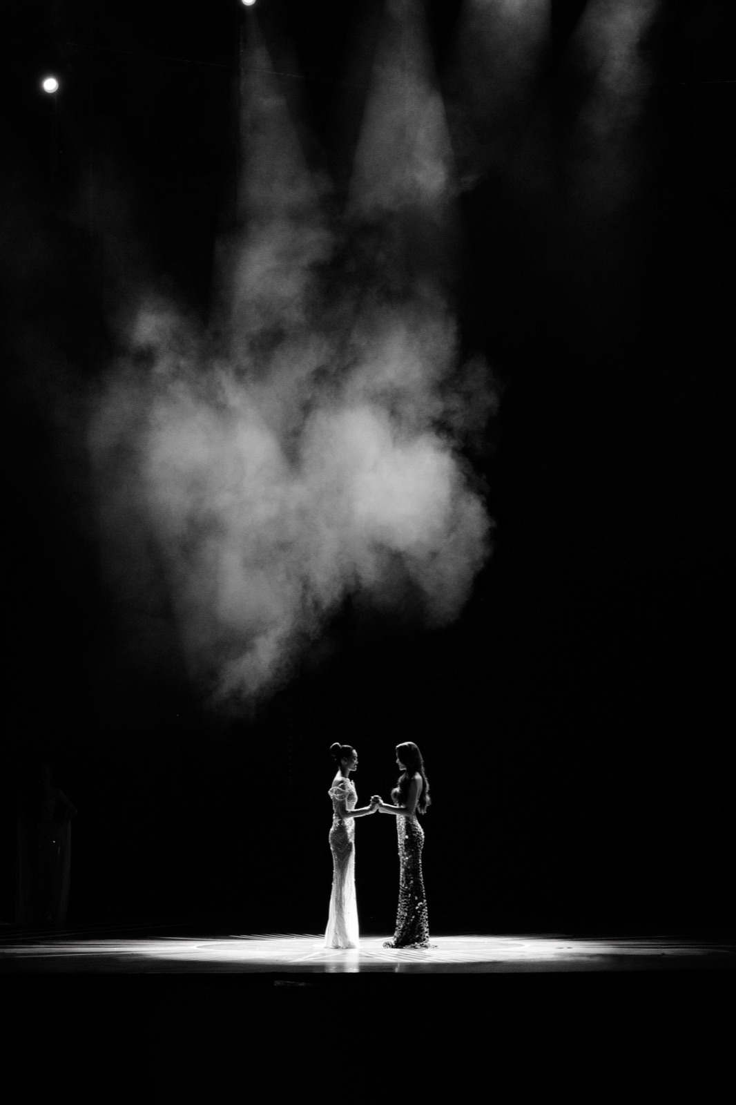 Two performers on a smoke-filled stage under dramatic theatre lighting
